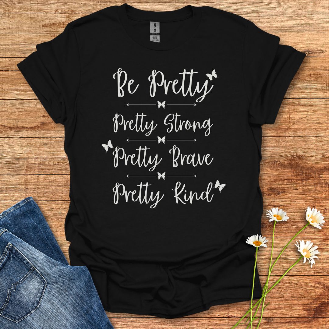 Black t-shirt with motivational quote on a wooden surface with jeans and flowers.